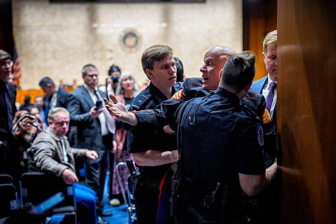 Brian McGinnis, a protester dressed in a military uniform, gets stuck in a door, injuring his arm, as Sen. Tim Sheehy, a Montana Republican, and U.S. Capitol Police officers attempt to remove him from a Senate Armed Services Subcommittee hearing on Capitol Hill on March 4, 2026 in Washington, DC. The protester has been identified as Brian McGinnis from North Carolina. The Subcommittee on Readiness and Management Support is holding a hearing to examine the current readiness of the Joint Force.