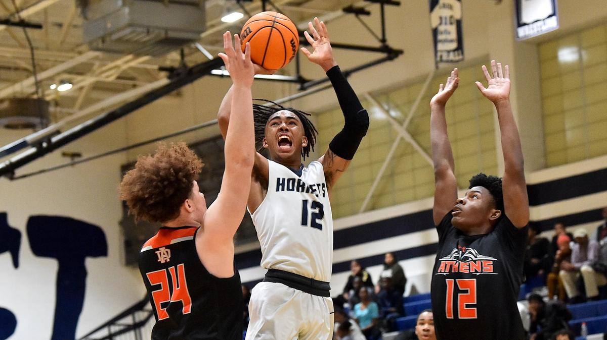 Hillside’s Trey Crews (12) attempts the jump shot against Athens Drive’s Elijah Harris (24) and Ke’Avion Hudgins (12) during the fourth quarter. The Hillside Hornets and the Athens Drive Jaguars met in a basketball game in Durham, N.C. on January 24, 2020.