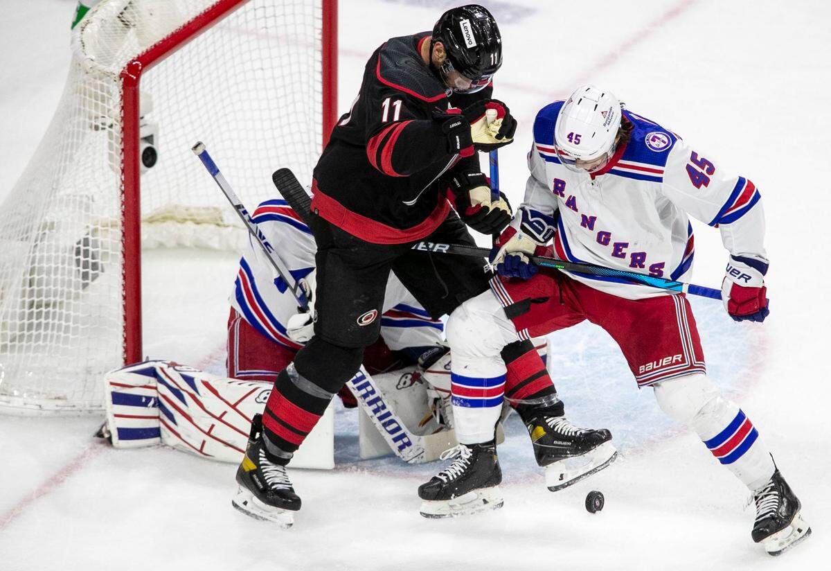 The Carolina Hurricanes’ Jordan Staal (11) works to control the puck against against New York Rangers’ Branden Schneider (45) after a save by New York Rangers’ goalie Igor Shesterkin (31) during the first period on Thursday, May 26, 2022 during game five of the Stanley Cup second round at PNC Arena in Raleigh, N.C.