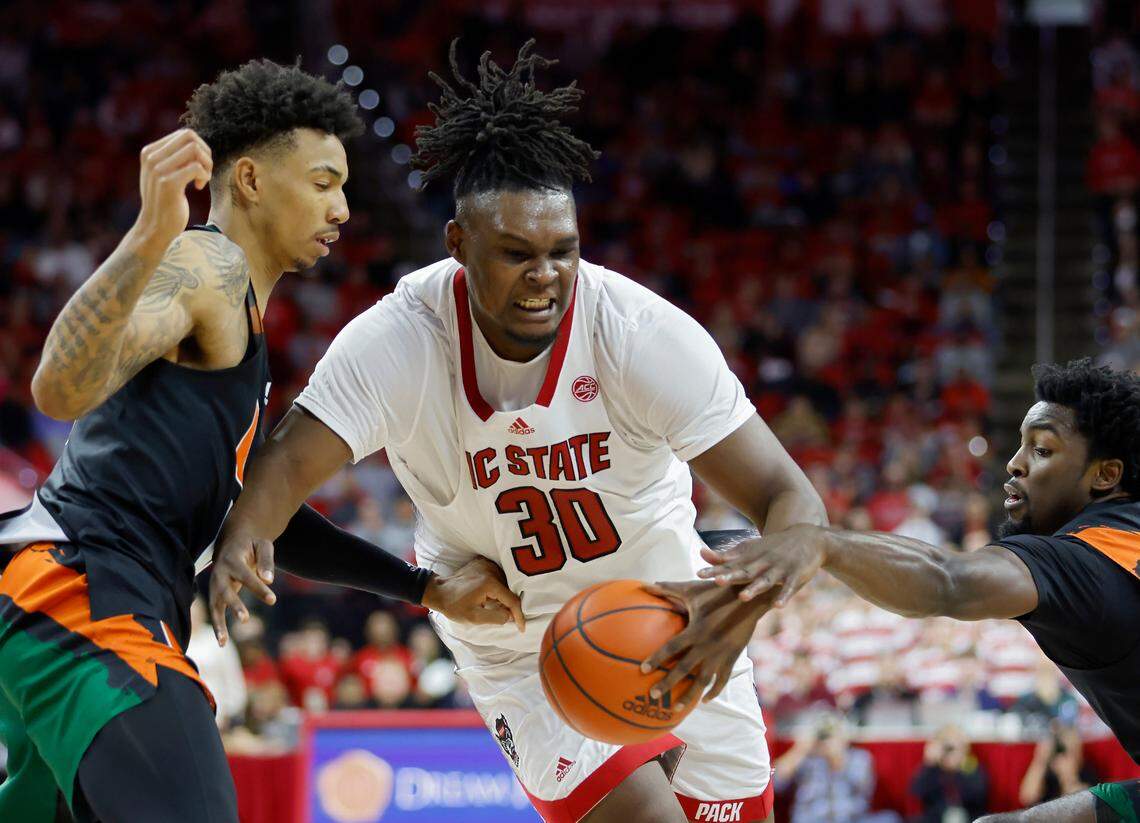 N.C. State’s D.J. Burns Jr. drives between Miami’s Jordan Miller and Bensley Joseph during the second half of a men’s basketball game at PNC Arena on Saturday, Jan. 14, 2023, in Raleigh, N.C.