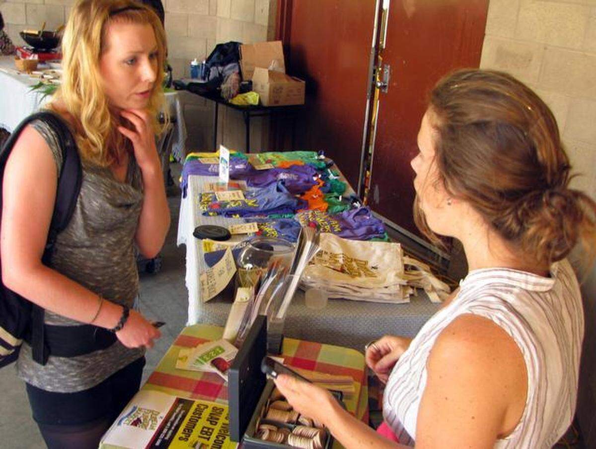 Durham resident Mary Kate Cardin (left) talks with Jenny Elander about the Double Bucks program Wednesday, Aug. 6, 2014, at the Durham Farmer’s Market on Foster Street. The Double Bucks program gives customers shopping with EBT cards – federal food benefits – and other vouchers up to $10 extra to spend on fresh fruits and vegetables.