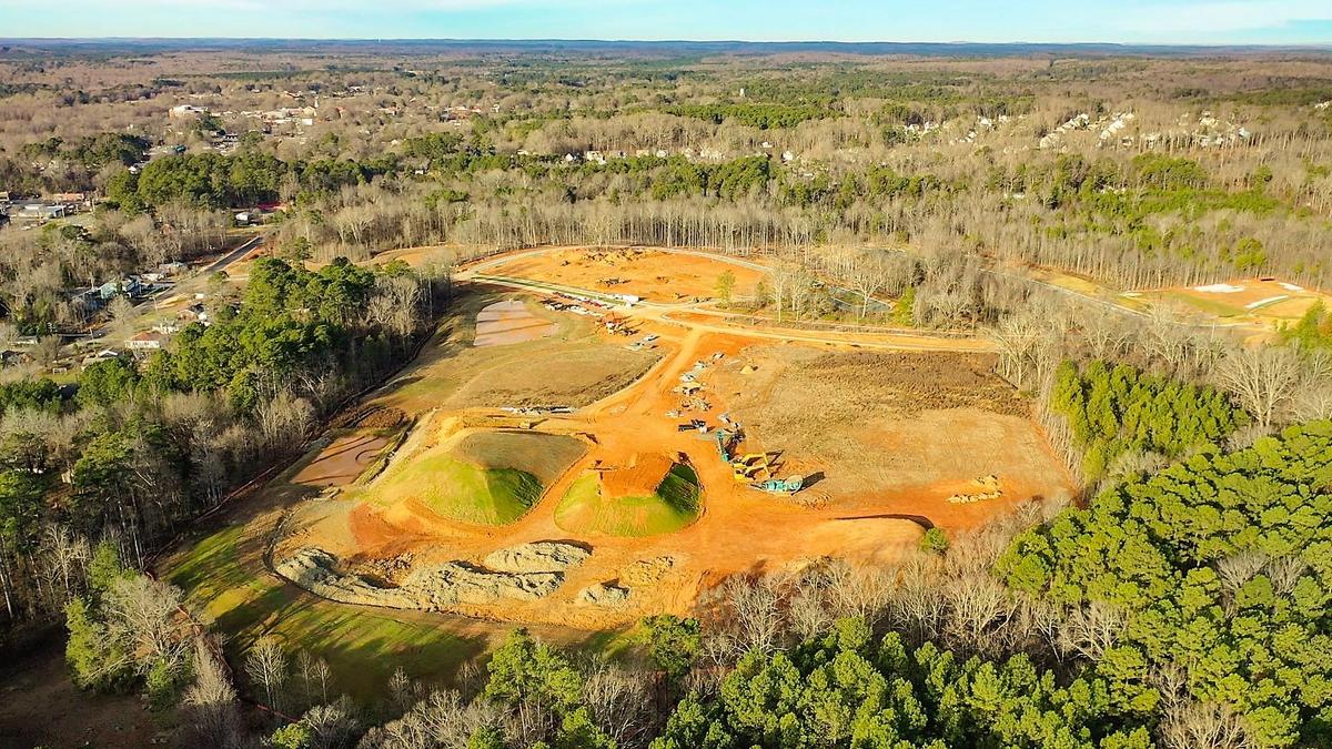 A drone view of the first building site in The Vineyards shows downtown Pittsboro at the top left, The Cottages site at the top center, and cleared land for a new park in the center. Thales Academy would be built in the wooded area at the bottom of the photo.