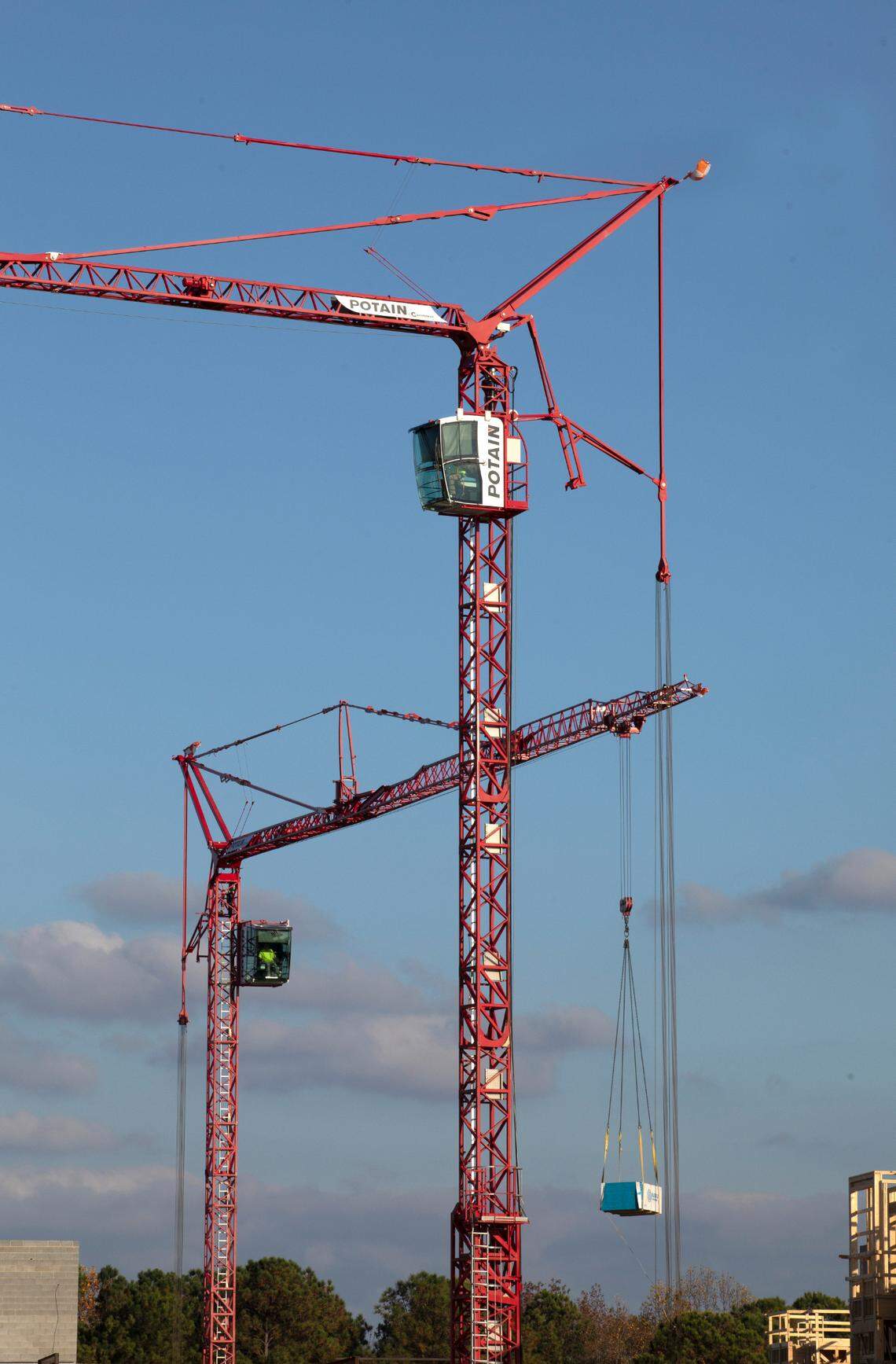 Two large cranes move material during the construction of a new phase of the Searstone Retirement Community in Cary, Nov. 3, 2022.