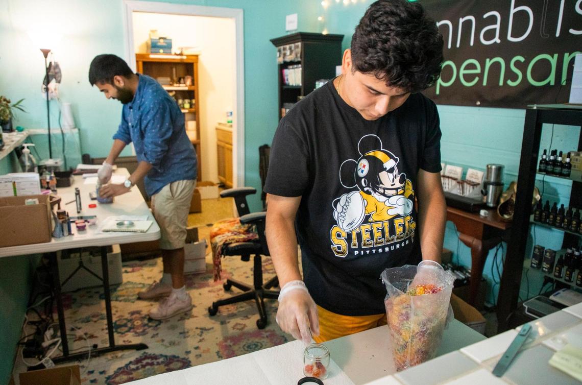 Amado Ruiz-Perez, right, fills jars with CBD gummies at Cannabliss Dispensary, on Wednesday, July 7, 2021, in Chapel Hill, N.C.