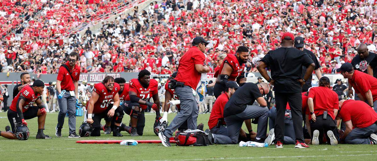 Players watch as N.C. State quarterback Grayson McCall is attended to after being injured during the first half of N.C. State’s game against Wake Forest at Carter-Finley Stadium in Raleigh, N.C., Saturday, Oct. 5, 2024.