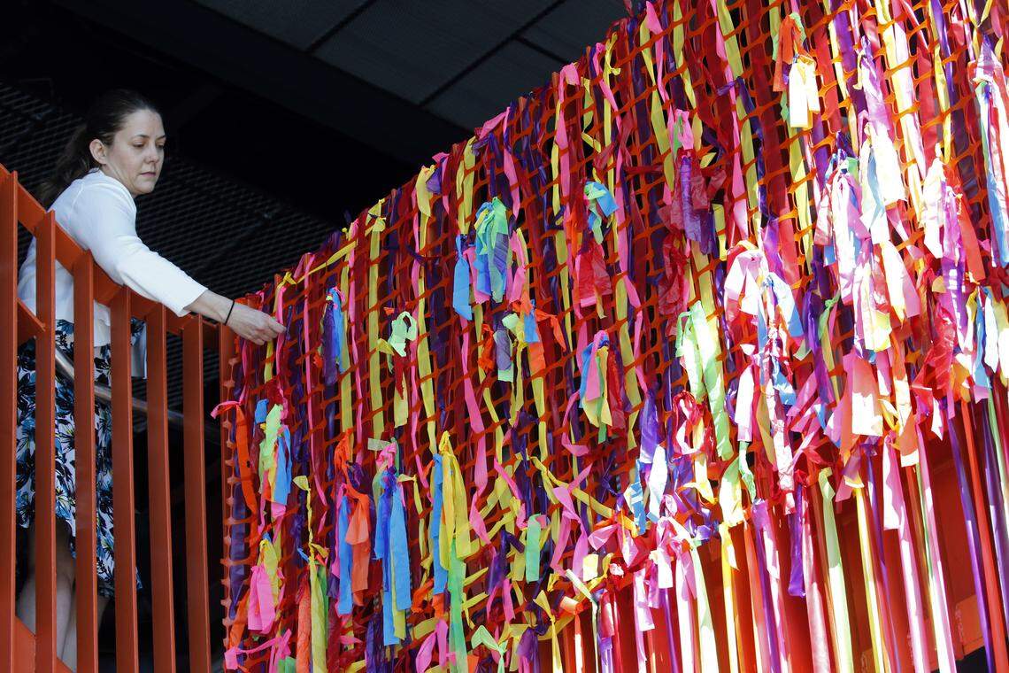 A visitor takes a piece of a multi-colored ceremonial ribbon made of dozens of strands as the new Raleigh Union Station has its grand opening downtown on Monday, April 30, 2018.  Everyone was encouraged to take a snip and a souvenir piece of ribbon with them after the formal cuttings.