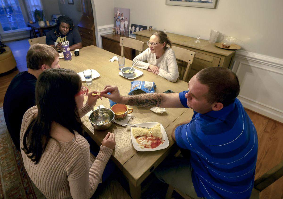Lexi, left, eats dinner at home in Carrboro with the Caraway family.