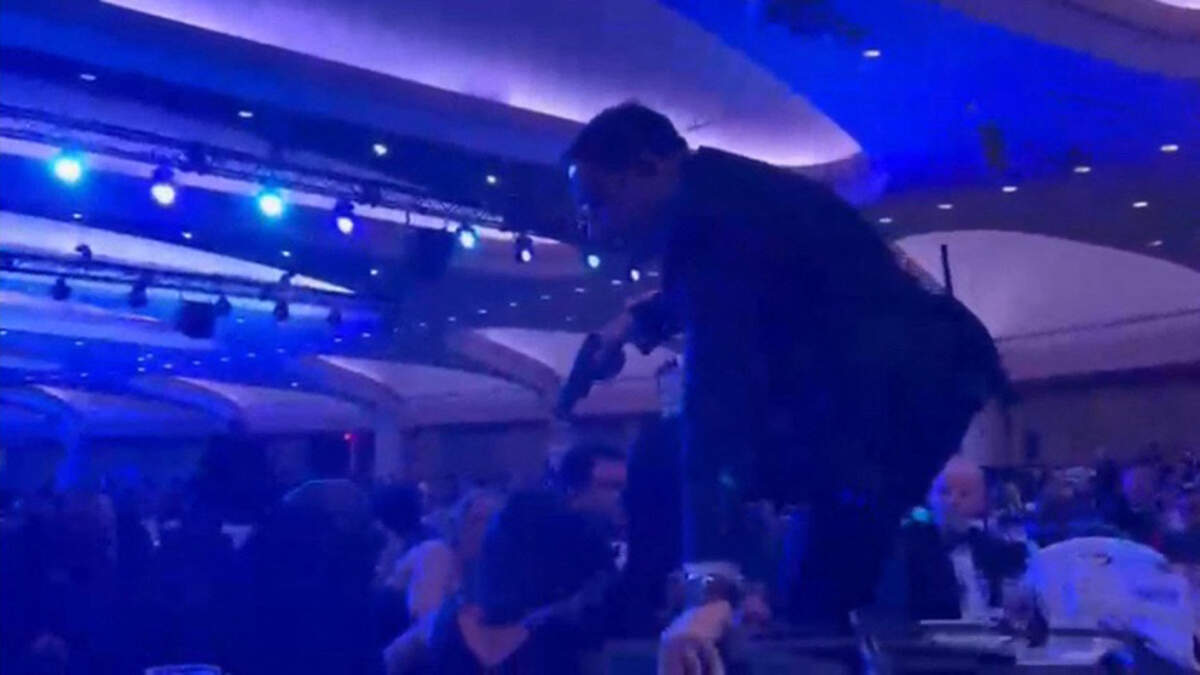 A screen grab taken from a video filmed by an AFP reporter shows an armed agent climbing over chairs as they move to the stage after loud bangs were heard during the White House Correspondents' dinner at the Washington Hilton in Washington, DC, on April 25, 2026. Shots were fired as US President Donald Trump attended a press dinner in Washington on Saturday night, witnesses and AFP reporters confirmed. Loud bangs were heard and guests at the black-tie White House Correspondents' Dinner scrambled to hide under tables.