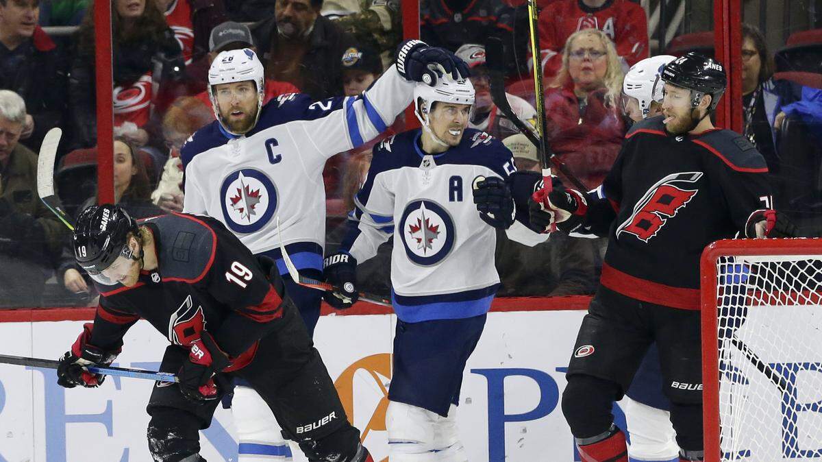 The Winnipeg Jets’ Blake Wheeler (26) and Mark Scheifele celebrate following Wheeler’s goal while Carolina Hurricanes defensemen Dougie Hamilton (19) and Jaccob Slavin, right, skate away during the first period of the Hurricanes’ 8-1 loss Friday night.