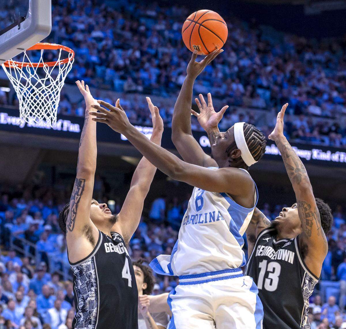 North Carolina forward Caleb Wilson (8) puts up a shot against Georgetown forward Jaydon Young (4) and guard Langston Love (13) in the second half on Sunday, December 7, 2025 at the Smith Center in Chapel Hill, N.C.  Wilson lead the Tar Heels with 20 points in their 81-61 victory.