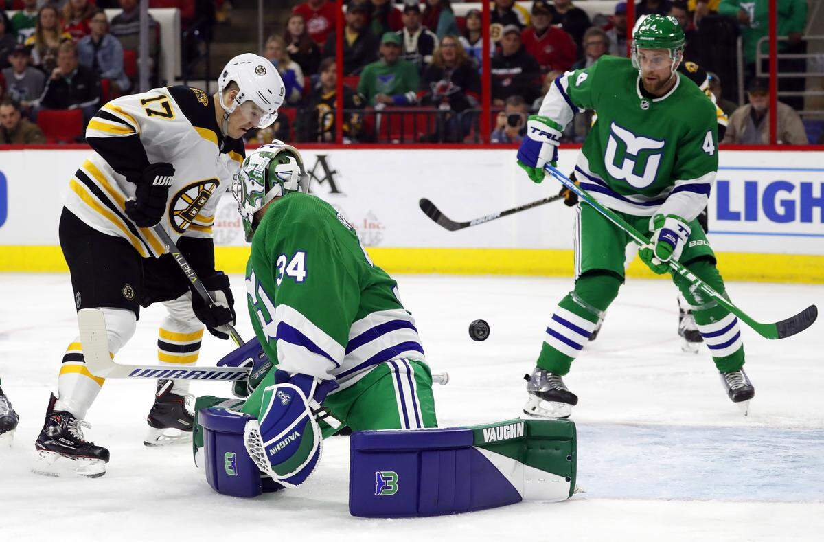 Boston Bruins’ Ryan Donato (17) pushes the puck past Carolina Hurricanes goaltender Petr Mrazek (34) with Calvin de Haan (44) nearby during the first period of an NHL hockey game, Sunday, Dec. 23, 2018, in Raleigh, N.C. (AP Photo/Karl B DeBlaker)