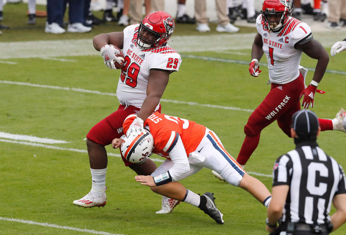 N.C. State defensive tackle Alim McNeill (29) avoids the tackle by Virginia quarterback Lindell Stone (36) as he returns an interception for a touchdown during the second half of N.C. State’s 38-21 victory over Virginia at Scott Stadium in Charlottesville, Va., Saturday, Oct. 10, 2020.