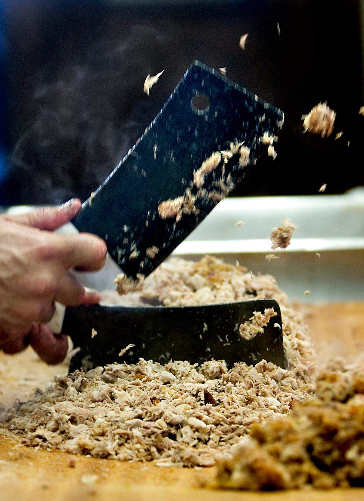 Barbecue is chopped at The Skylight Inn using two cleavers on a wooden block.