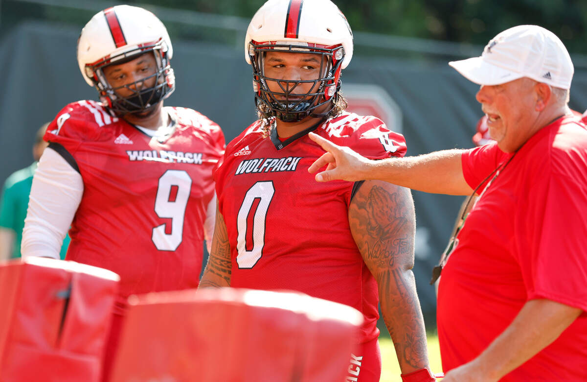 N.C. State defensive end Savion Jackson (9) and defensive tackle Joshua Harris (0) listen to defensive line coach Charley Wiles during the Wolfpack’s first practice of fall camp in Raleigh, N.C., Wednesday, August 3, 2022.