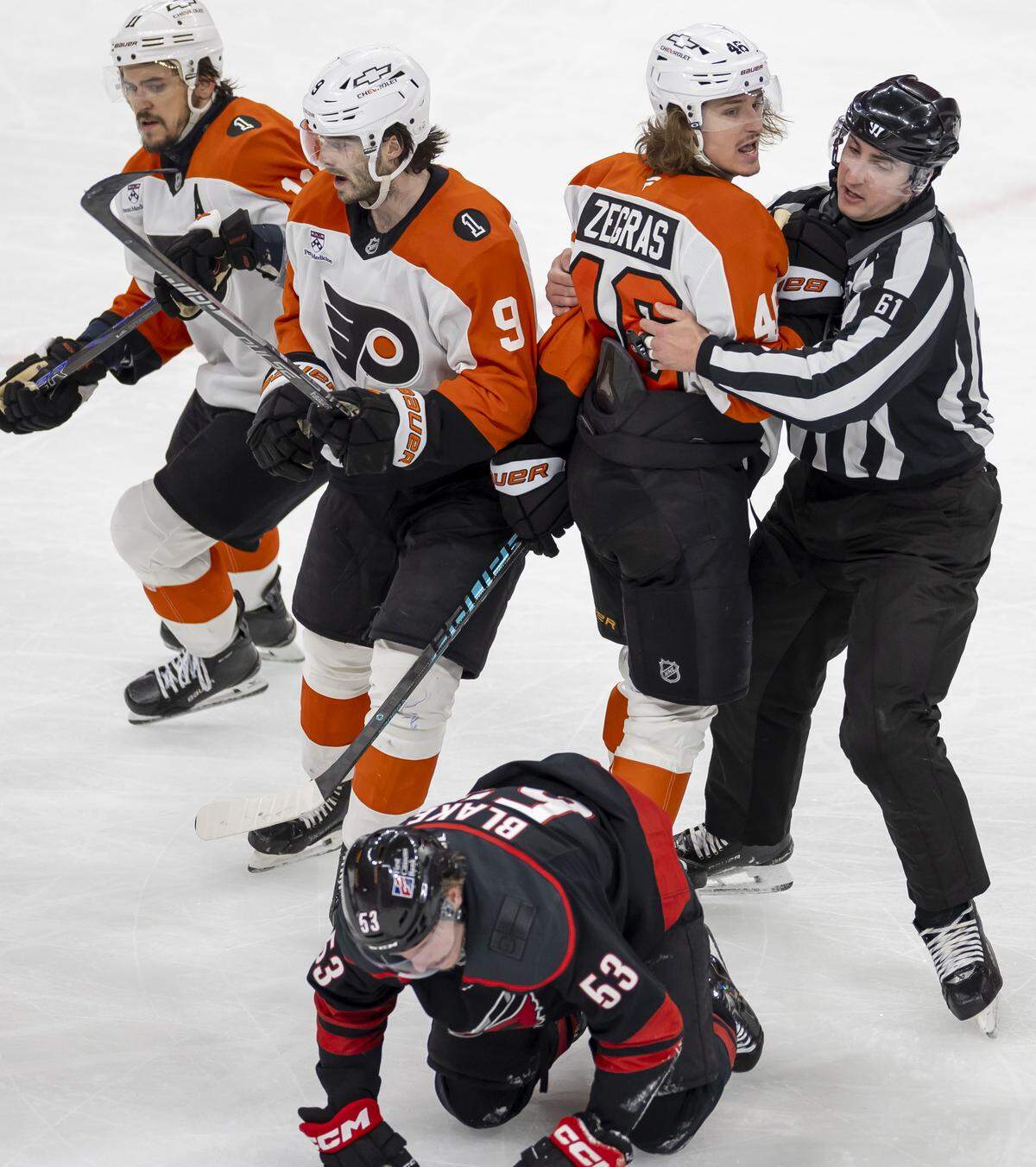 Official James Tobias restrains Philadelphia center Trevor Zegras after an altercation with Carolina Hurricanes Jackson Blake (53) in the third period of Game 1 on Saturday, May 2, 2026, during the second round of the Stanley Cup Playoffs at Lenovo Center in Raleigh, N.C.