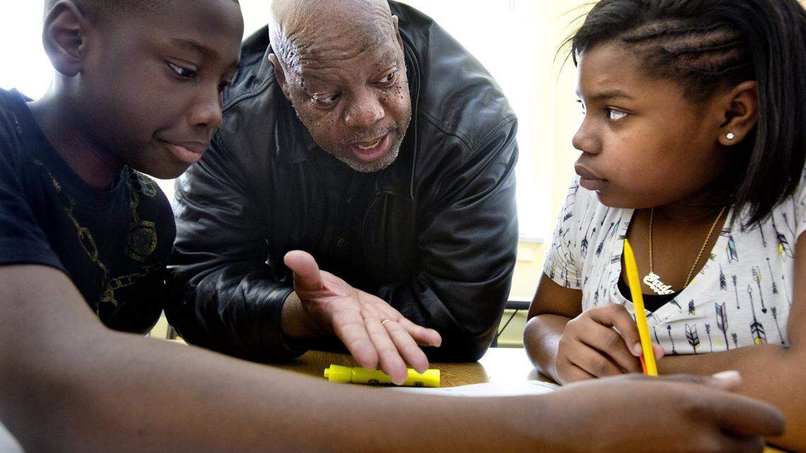 Dr. Patrick Wilson, 64, of Franklinton, center, tutors 5th grade students, Grandell Thompson, left and Jada Smith, right, on math problems as a volunteer at Hunter Elementary School in Raleigh in this 2015 file photo. The N.C. Education Corps is recruiting people who will be paid to do things such as tutor students in public schools..