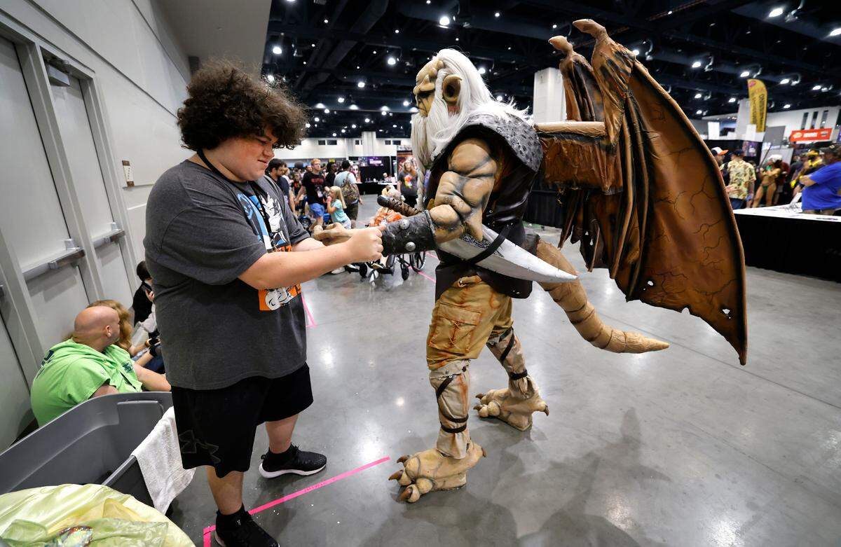 Jesse Melvin helps his uncle Rocky Melvin put his hands on while attending GalaxyCon Raleigh at the Raleigh Convention Center Sunday, July 28, 2024. Rocky is dressed as Hudson from Gargoyles.