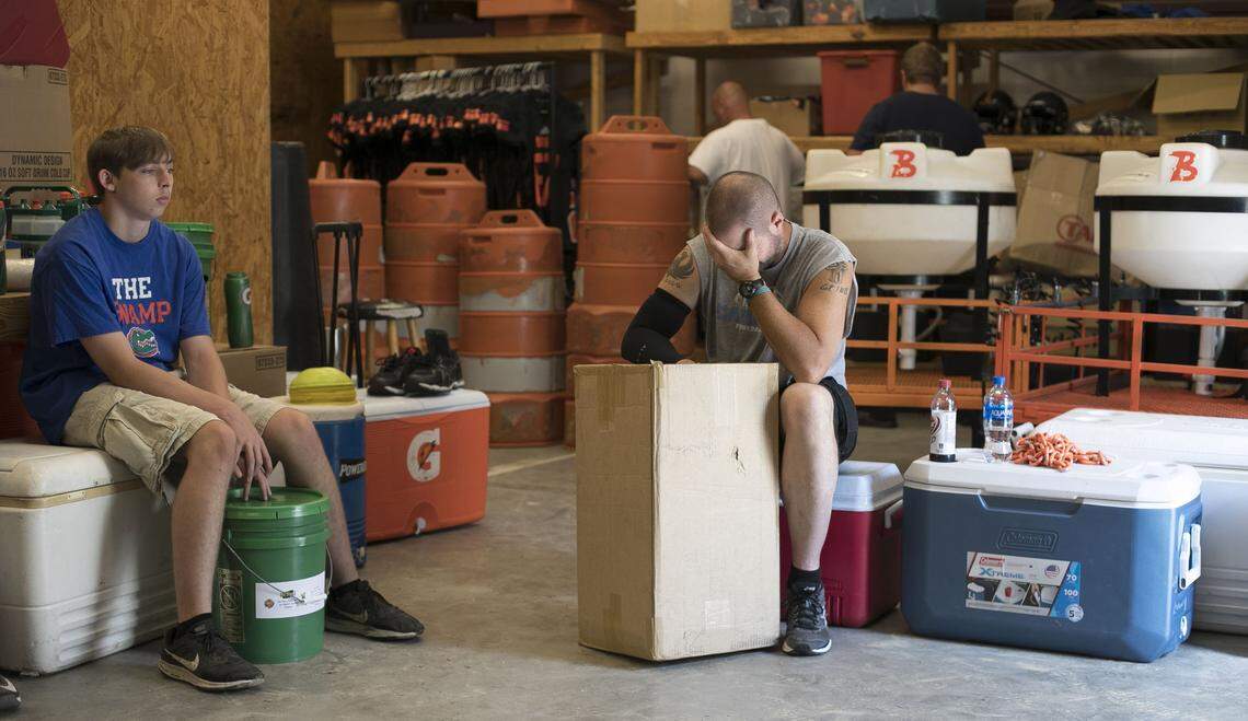 Wallace-Rose Hill coach Kevin Motsinger takes a moment to gather himself as he hands out socks to players who lost their clothing to the flood waters following Hurricane Florence, as the team prepared to play their first game in nearly a month on Friday, October 5, 2018 in Teachey, N.C.