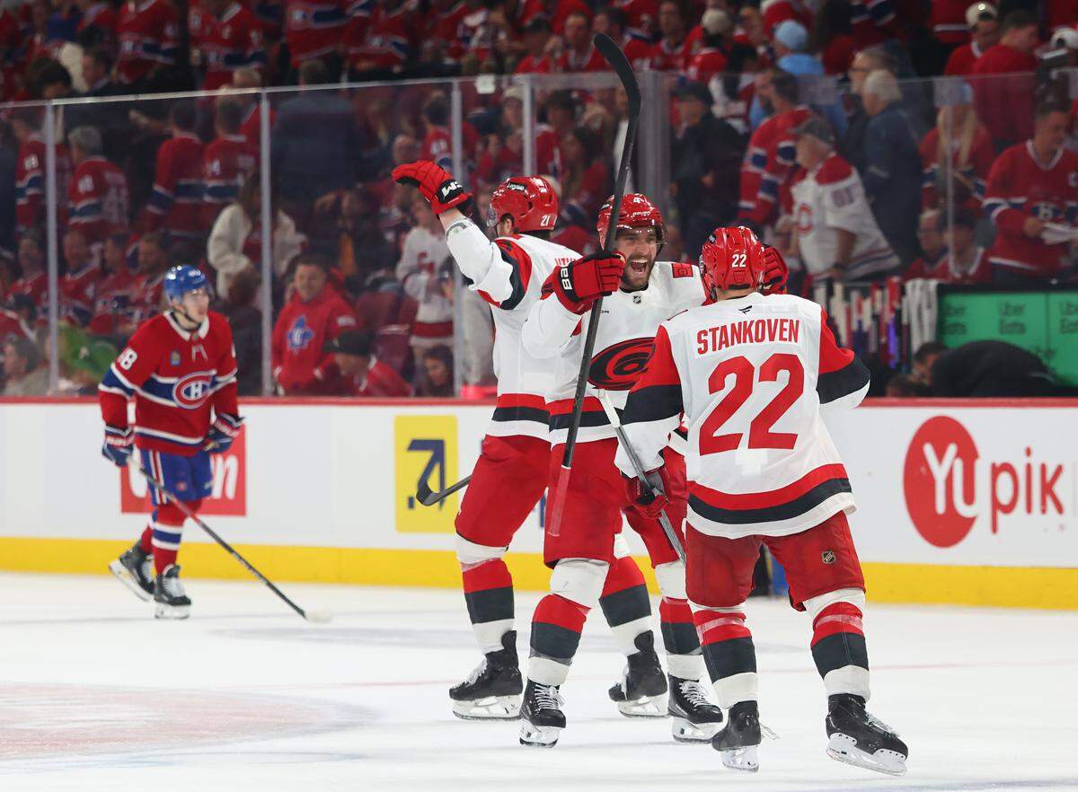 Logan Stankoven (22) of the Carolina Hurricanes celebrates with teammate Shayne Gostisbehere celebrate after defeating the Montréal Canadiens 3-2 in overtime in Game 3 of the Eastern Conference Final of the 2026 Stanley Cup Playoffs at Bell Centre on May 25, 2026 in Montreal, Quebec, Canada.
