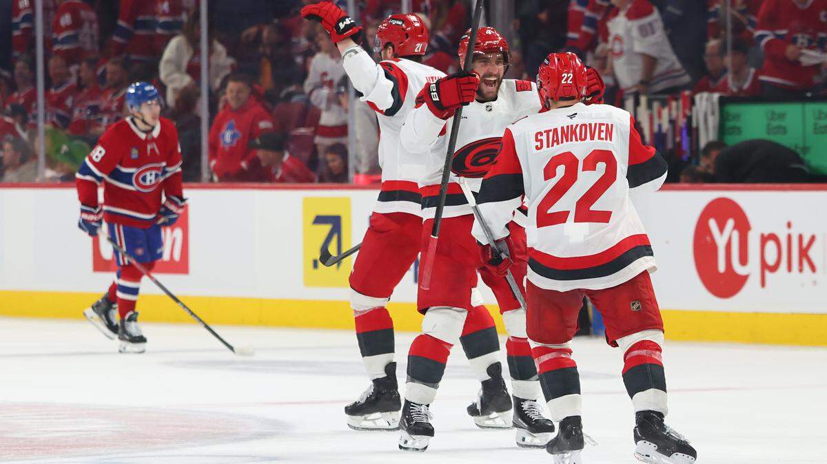 Logan Stankoven (22) of the Carolina Hurricanes celebrates with teammate Shayne Gostisbehere celebrate after defeating the Montréal Canadiens 3-2 in overtime in Game 3 of the Eastern Conference Final of the 2026 Stanley Cup Playoffs at Bell Centre on May 25, 2026 in Montreal, Quebec, Canada.