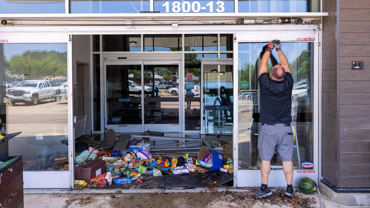 Workers secure the entrance of an Aldi grocery store in Eastgate Crossing in Chapel Hill on Monday, July 7, 2025, after floodwaters surged about 5 feet inside businesses at the shopping center. The flooding was caused by heavy rain from Tropical Storm Chantal, which triggered flash flooding in parts of Orange, Durham, and Chatham counties.