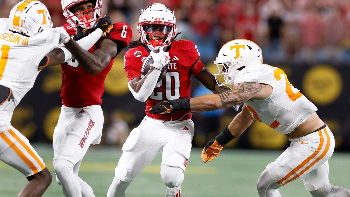 N.C. State running back Hollywood Smothers (20) gains yards as Tennessee linebacker Jeremiah Telander (22) looks to tackle him during the first half of N.C. State’s game against Tennessee in the Duke’s Mayo Classic at Bank of America Stadium in Charlotte, N.C., Saturday, Sept. 7, 2024.