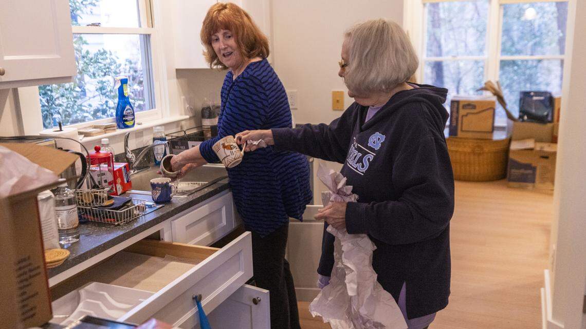 Catherine Burke, right, and her friend Terry Tucker unpack kitchenware in Burke’s newly renovated 1,380-square-foot home in the Weatherhill Pointe neighborhood in Carrboro. It was flooded in July 2025 by Tropical Storm Chantal.