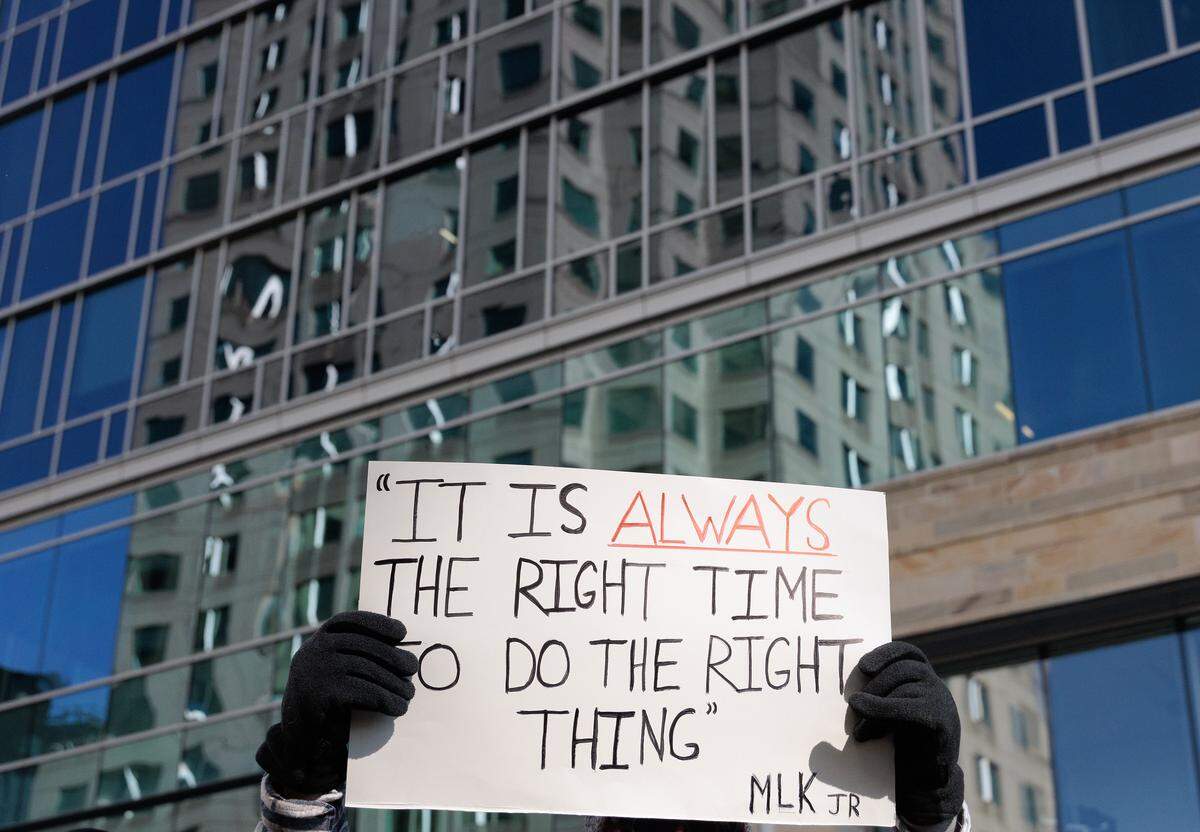 A person holds a sign aloft while walking along Fayetteville Street during the 46th Annual Martin Luther King Jr. Memorial March in Raleigh.
