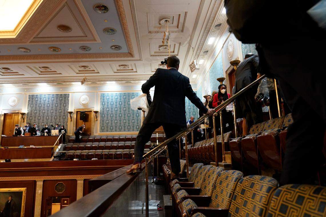 People shelter in the House gallery as rioters try to break into the House Chamber at the U.S. Capitol on Wednesday, Jan. 6, 2021, in Washington.