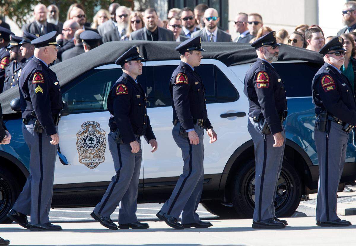 Police walk by a Raleigh Police Department vehicle draped in black prior to the funeral for police officer Gabriel Torres at Cross Assembly Church on Saturday, Oct. 22, 2022, in Raleigh, N.C. Torres, 29, was one of five people fatally shot in Raleigh on Oct. 13.