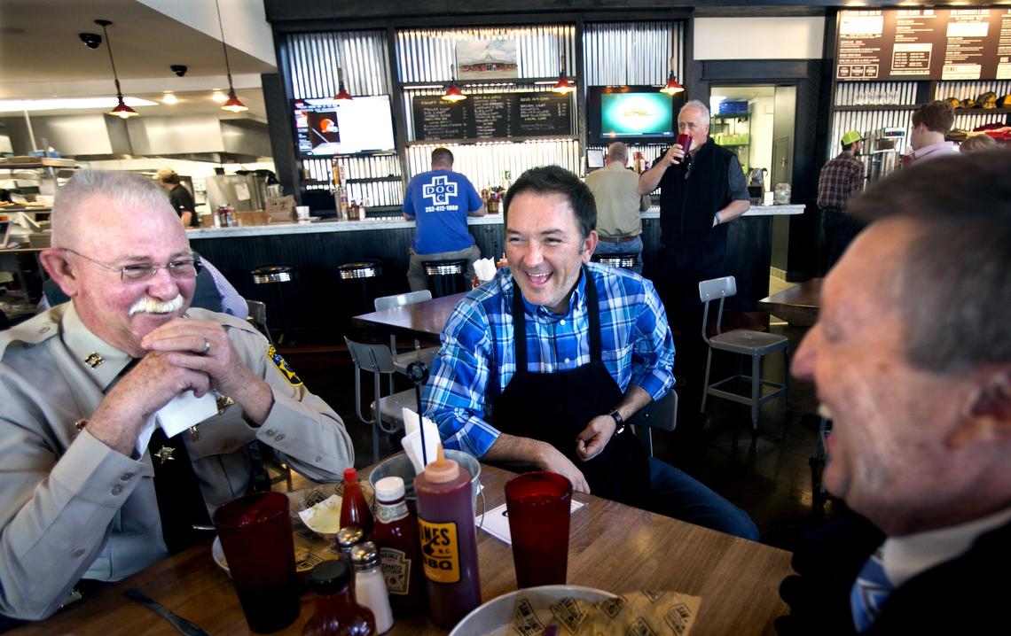 Sheriff Captain Robin Abbott, of Greenville, left, and Joe Nelson, of Winterville, right, get a visit from Sam Jones, center, during their lunch at Sam Jones BBQ in Winterville, N.C. in 2016.