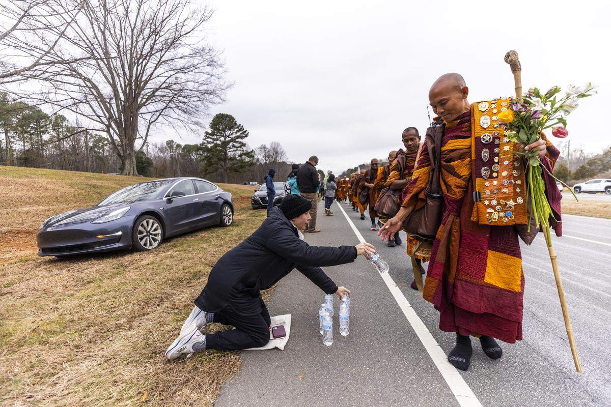 A small procession of Buddhist monks walks along U.S. Highway 64 west of Pittsboro on Thursday, Jan. 22, 2026, as hundreds of onlookers line the highway to welcome them. The monks are making a 2,300-mile pilgrimage from Texas to Washington, D.C., as part of the “Walk for Peace,” an effort to promote peace, compassion and national unity.