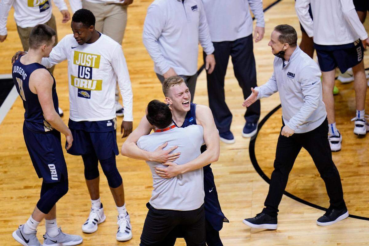 Oral Roberts forward Francis Lacis, center, celebrates with a coach after a college basketball game against Florida in the second round of the NCAA tournament at Indiana Farmers Coliseum, Sunday, March 21, 2021 in Indianapolis. Oral Roberts won 81-78. 