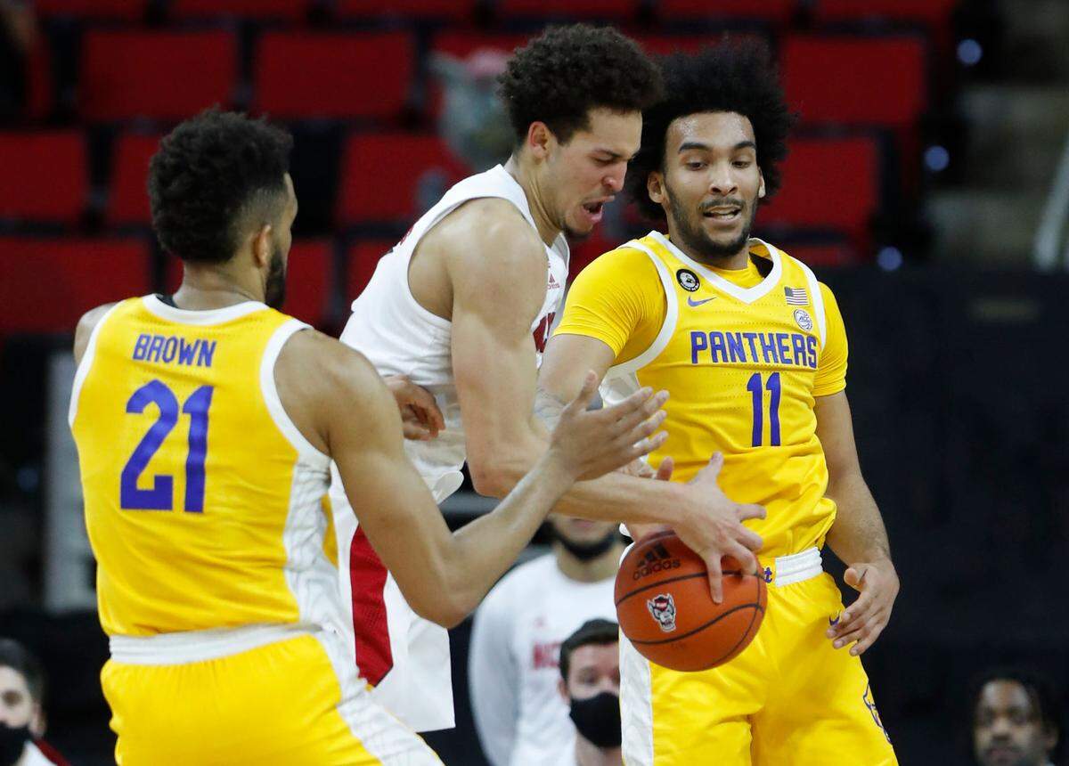 N.C. State’s Jericole Hellems (4) fights for a rebound between Pittsburgh’s Terrell Brown (21) and Pittsburgh’s Justin Champagnie (11) during the first half of N.C. State’s game against Pittsburgh at PNC Arena in Raleigh, N.C., Sunday, February 28, 2021.