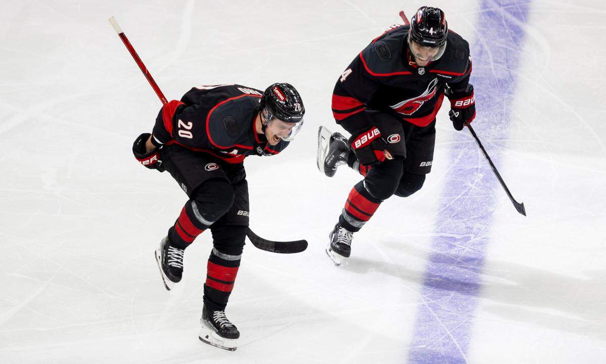 Carolina Hurricanes center Sebastian Aho (20) celebrates with teammate Shaye Gostisbehere (04) after scoring the game winning goal in double overtime to secure a 5-4 victory and clinch the first round Stanley Cup series over the New Jersey Devils on Tuesday, April 29, 2025 at Lenovo Center in Raleigh, N.C.