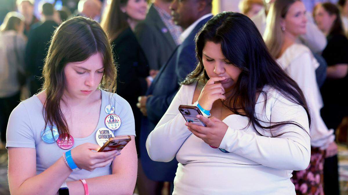 Teagan Anderson, left, and Mariana Garcia look over election results on their phones during a North Carolina Democratic Party election night event at the Marriott City Center in Raleigh, N.C., Tuesday, Nov. 5, 2024.