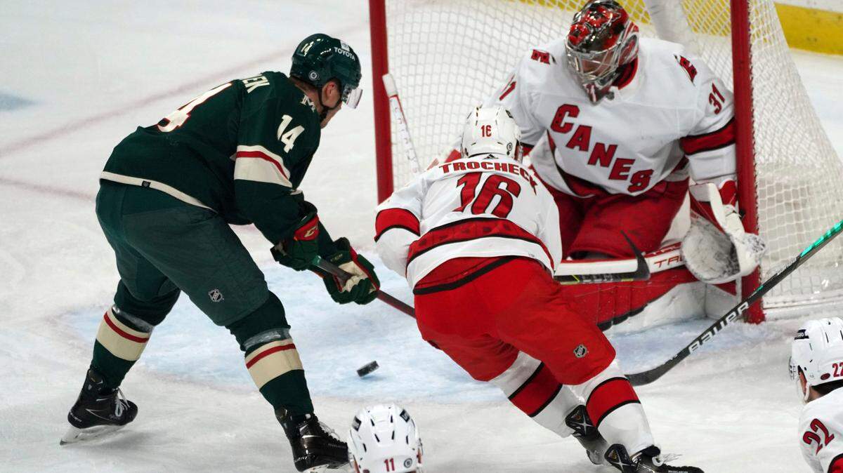 Minnesota Wild’s Joel Eriksson Ek (14) looks at a rebound as Carolina Hurricanes’ Derek Stepan (18) comes to the aid Hurricanes goalie Frederik Andersen (31) in the first period of an NHL hockey game, Saturday, Feb. 12, 2022, in St. Paul, Minn. (AP Photo/Jim Mone)