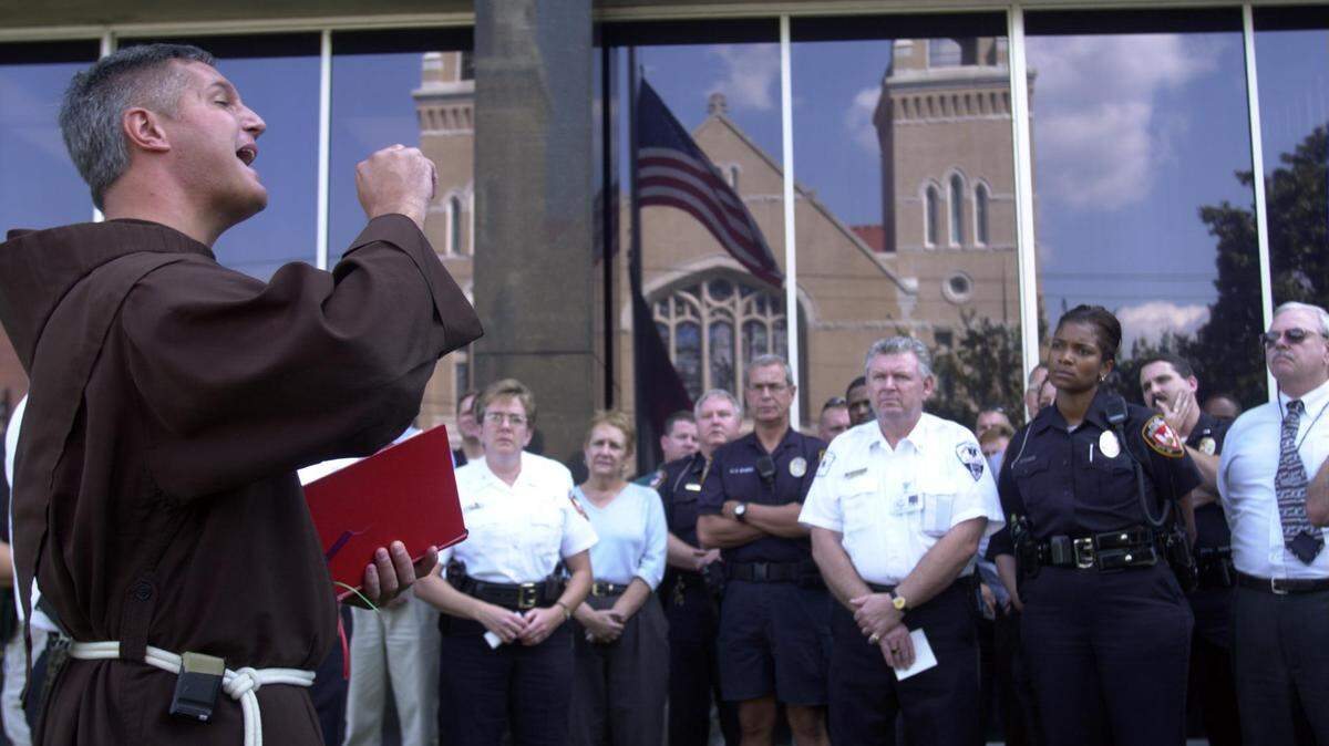 Father Patrick Tuttle, left, leads members of the Durham Police Department, EMS and Fire Departments in a prayer vigil in 2001 to pray for the victims of Sept. 11. Tuttle, who had a visible ministry presence in North Carolina previously, was most recently working in Macon.