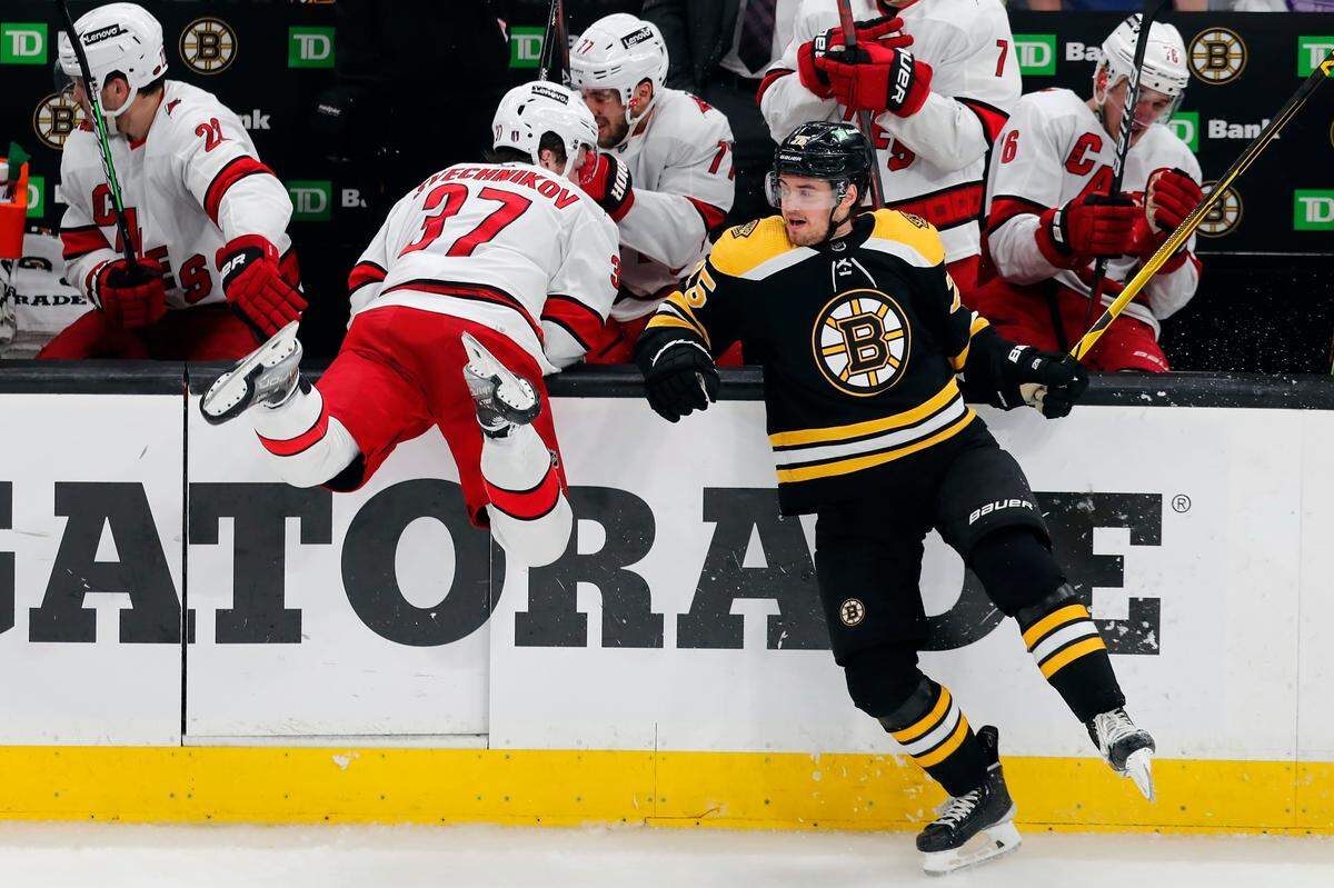 Boston Bruins’ Connor Clifton (75) checks Carolina Hurricanes’ Andrei Svechnikov (37) during the second period in Game 6 of an NHL hockey Stanley Cup first-round playoff series Thursday, May 12, 2022, in Boston.