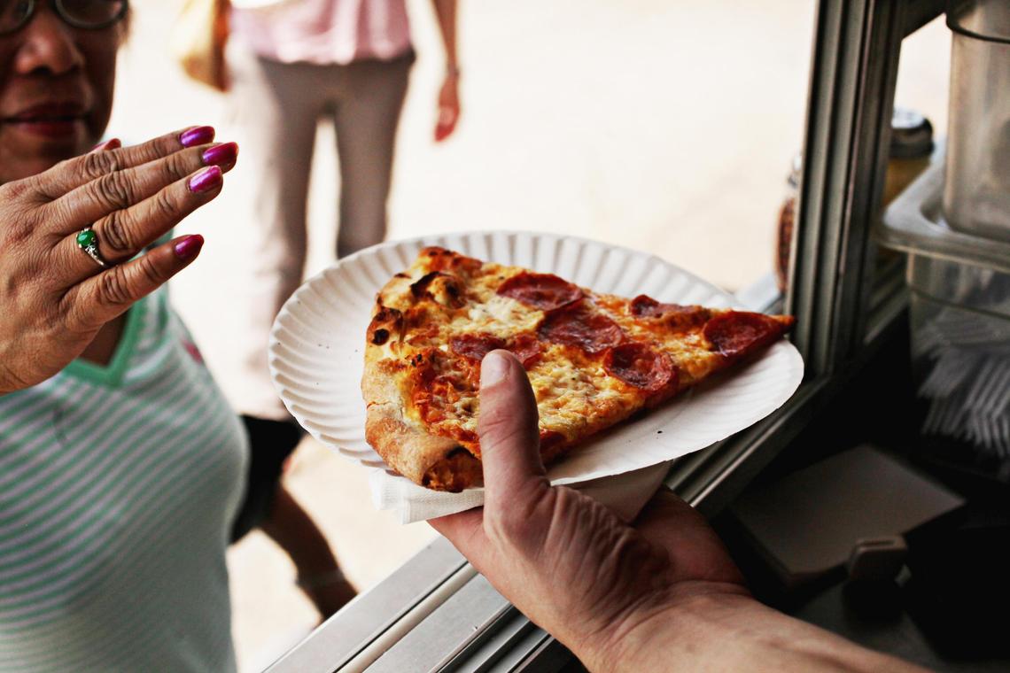 A fresh slice of pepperoni pizza is passed to a customer in the Pie Pushers’ truck on Wednesday, May 11, 2016, in Morrisville. The classic pepperoni is always a popular choice.