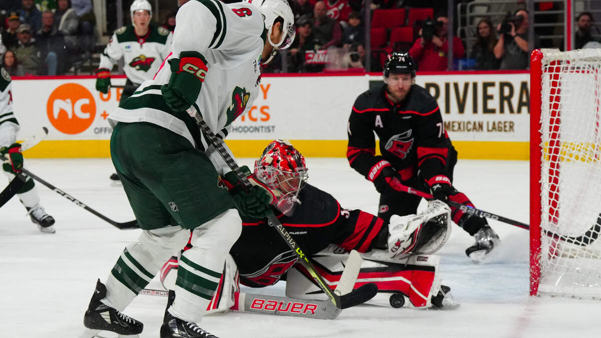 Jan 21, 2024; Raleigh, North Carolina, USA; Carolina Hurricanes goaltender Antti Raanta (32) stops the scoring attempt by Minnesota Wild defenseman Dakota Mermis (6) during the second period at PNC Arena. Mandatory Credit: James Guillory-USA TODAY Sports