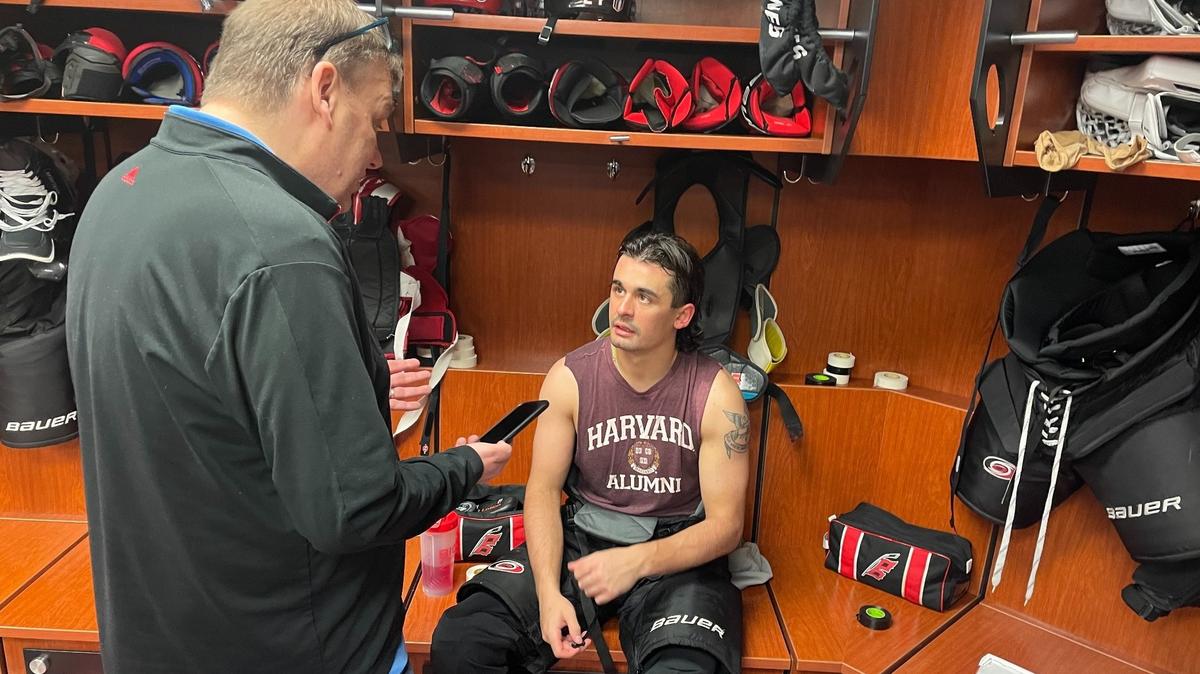 Carolina Hurricanes forward Seth Jarvis speaks to a reporter while wearing his beloved Harvard alumni T-shirt, a gift from teammate and actual Harvard alum Jack Drury.