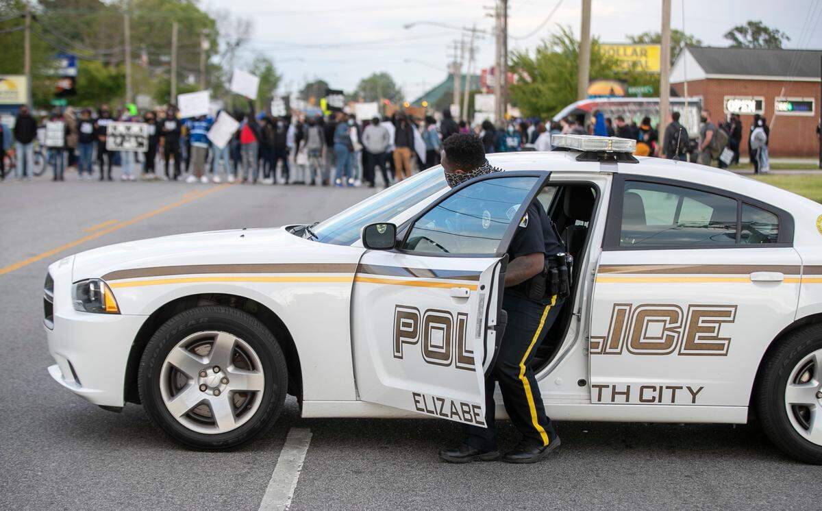 An Elizabeth City, NC police officer blocks Ehringhaus Street on Thursday, April 22, 2021 as demonstrators march through the busy retail district. More than 300 people marched through the streets in reaction to the death of Andrew Brown Jr., who was shot by a Pasquotank County Deputy Sheriff on Wednesday.