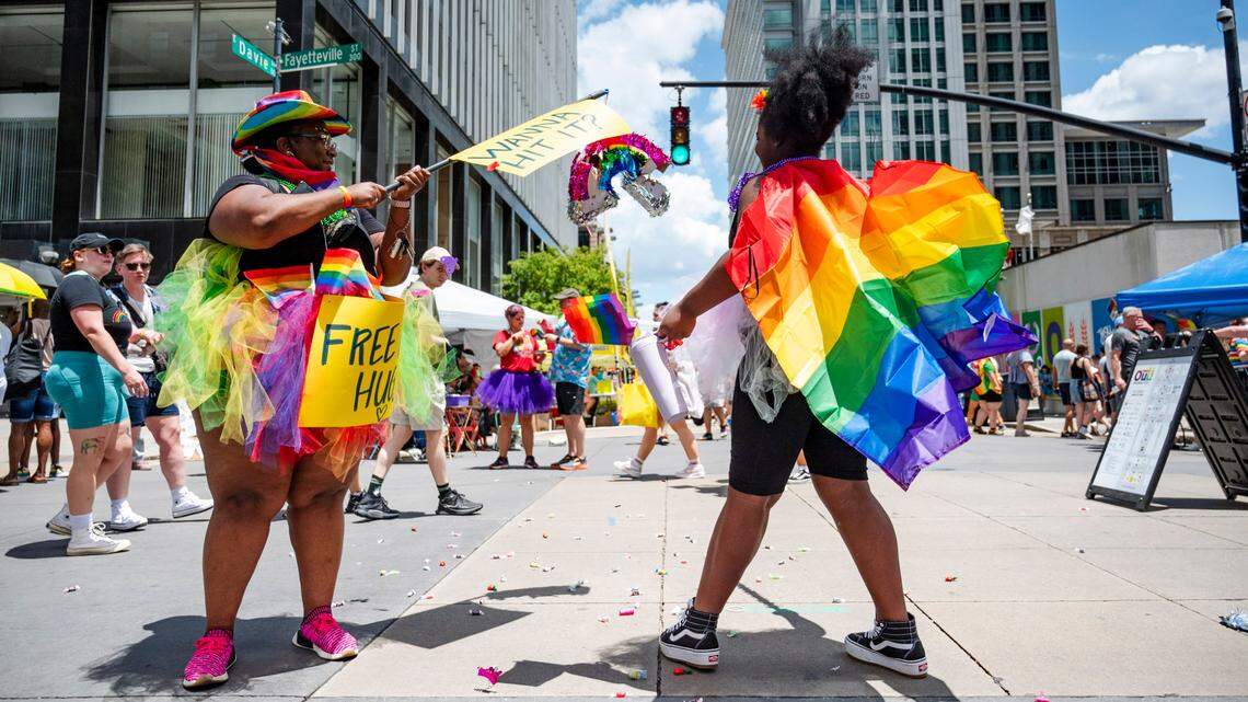 Ebony Hartsfield-Thorne holds a rainbow piñata while her daughter Athena swings at it releasing candy onto Fayetteville Street where Raleigh Pride took place on Saturday June 22, 2024.