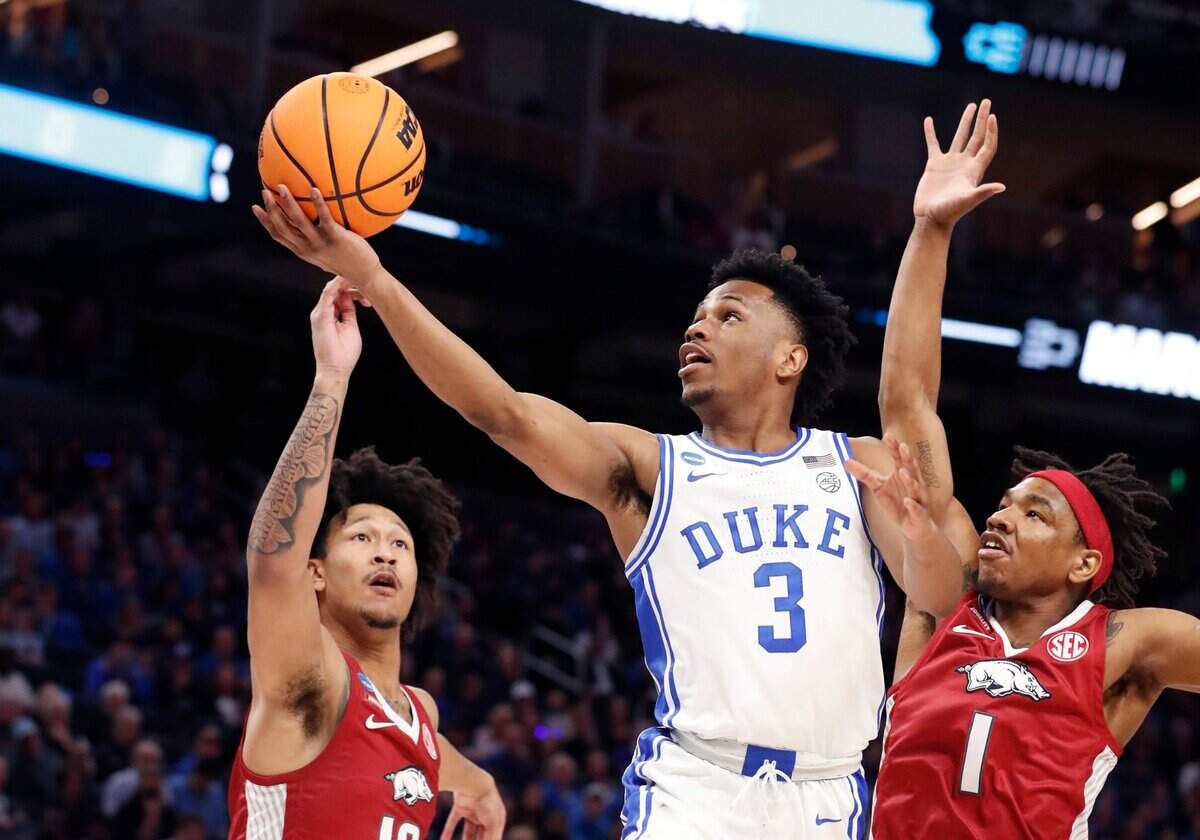 Dukes Jeremy Roach (3) drives to the basket between Arkansas’ Jaylin Williams (10) and JD Notae (1) during the first half of Dukes game against Arkansas in the NCAA Tournament West Regional finals at the Chase Center in San Francisco, Calif., Saturday, March 26, 2022.