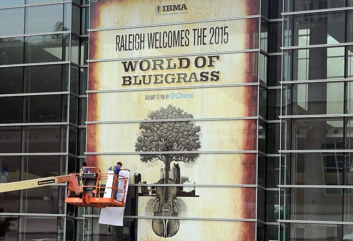 Rollo Gamez (left) and Nick Yager work on the 30 ft x 90 ft IBMA welcome sign they installed on the outside of the Raleigh Convention Center Monday, Sept. 28, 2015. They work for the Capitol Wraps company and the job took them 90 minutes to complete.