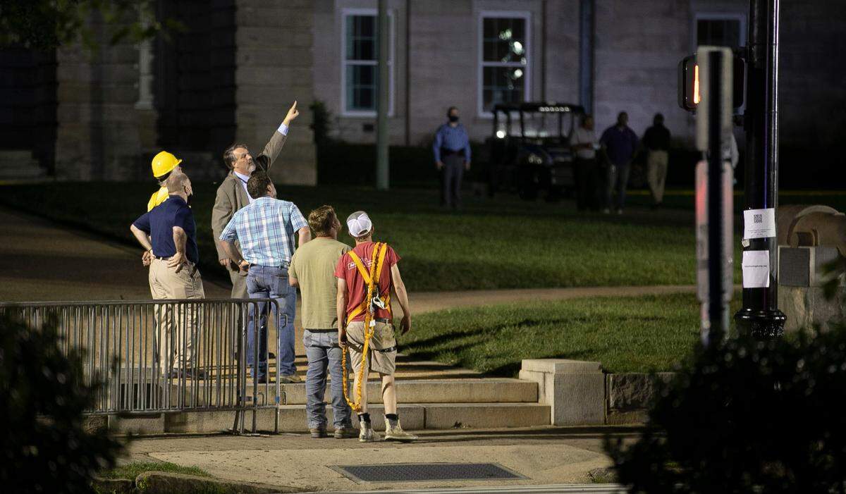 Crews huddle as they work to remove the Confederate monument on the west side of the North Carolina State Capital on Tuesday, June 23, 2020 in Raleigh, N.C. After four hours of working into the early morning hours without success, they discontinued their work at daybreak.