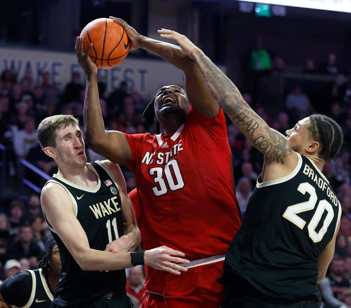 N.C. State’s D.J. Burns Jr. (30) shoots while being defended by Wake Forest’s Andrew Carr (11) and Davion Bradford (20) during the second half of N.C. State’s 79-77 victory over Wake Forest at Joel Coliseum in Winston-Salem, N.C., Saturday, Jan. 28, 2023.