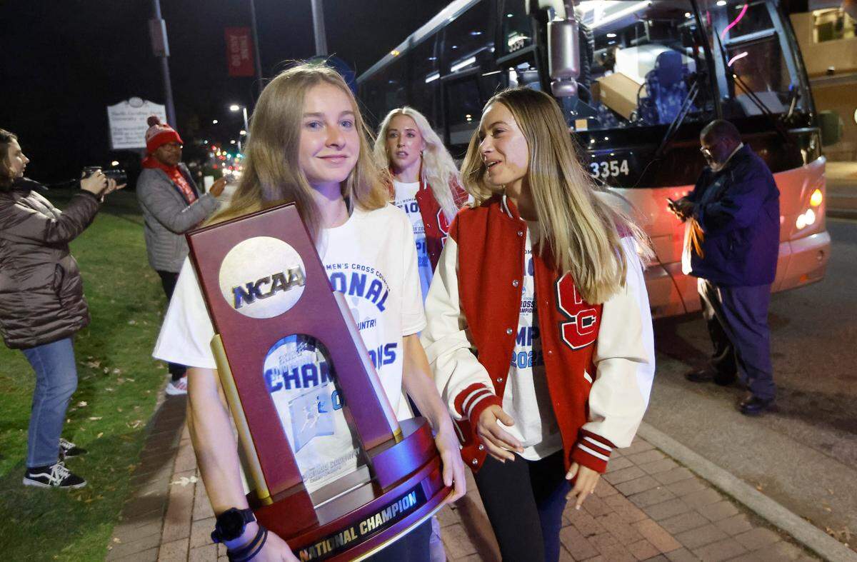 N.C. State’s Katelyn Tuohy holds the championship trophy as she, Sam Bush, right, and the rest of the Wolfpack women’s cross country team arrives at the Memorial Belltower in Raleigh after winning the NCAA Division I cross country championship Saturday, Nov. 19, 2022.