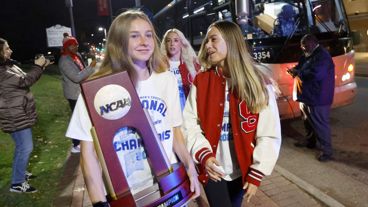 N.C. State’s Katelyn Tuohy holds the championship trophy as she, Sam Bush, right, and the rest of the Wolfpack women’s cross country team arrives at the Memorial Belltower in Raleigh after winning the NCAA Division I cross country championship Saturday, Nov. 19, 2022.